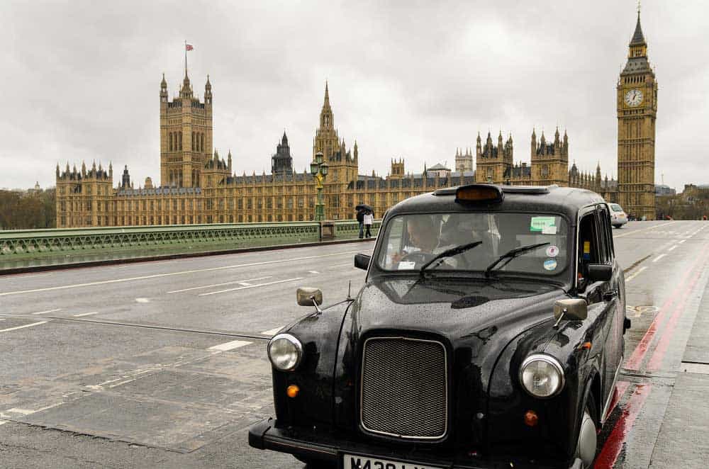 Typical black London cab on the Westminster Bridge in front of Houses of Parliament